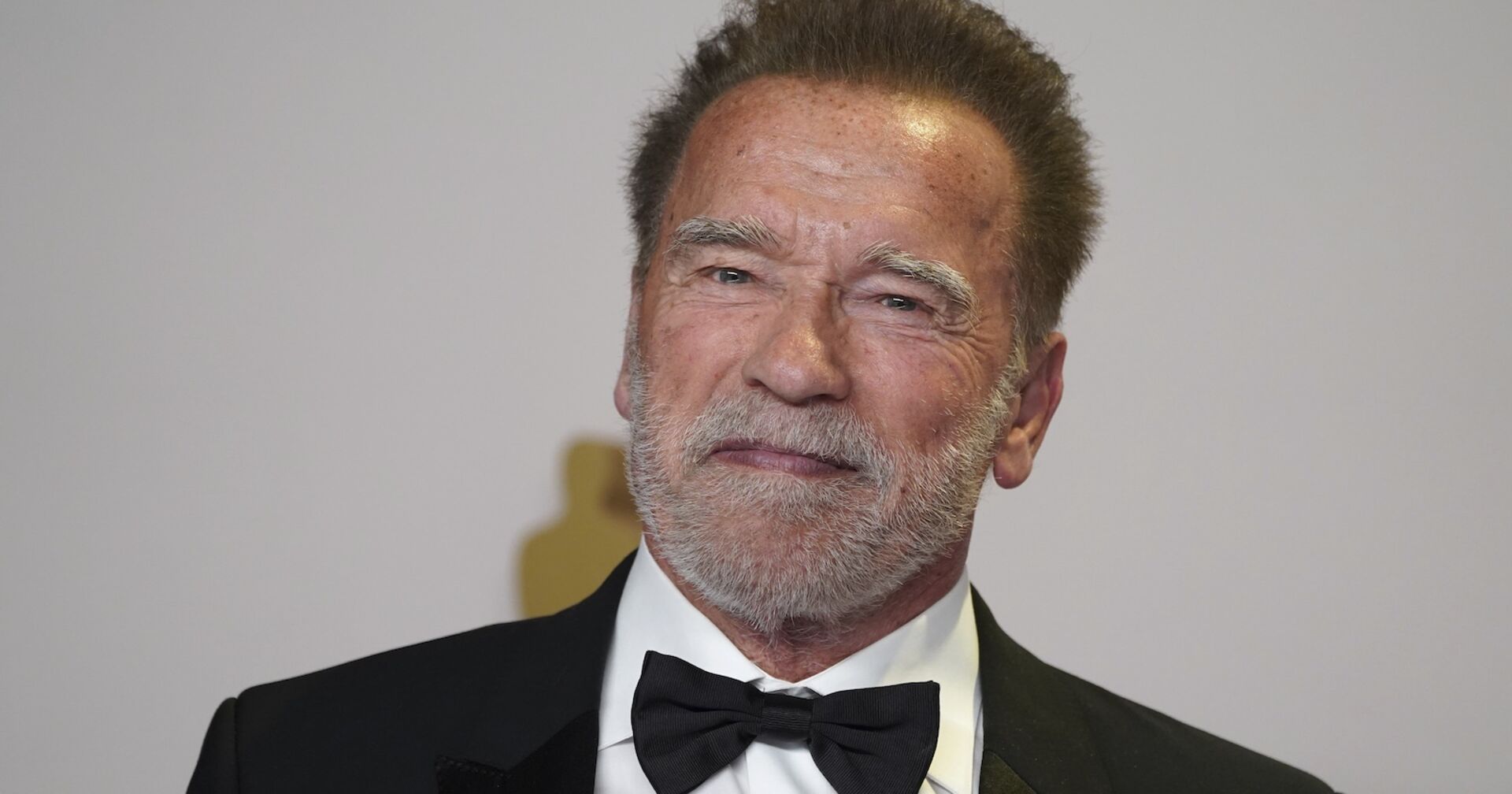 Arnold Schwarzenegger mit einem schwarzen Anzug und einer Fliege.