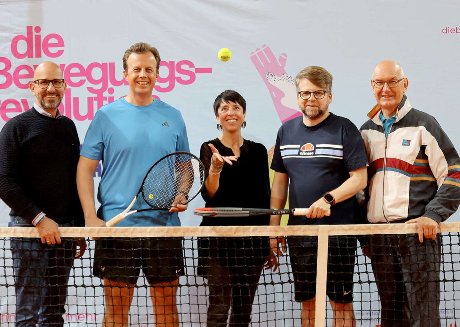 Vier Männer und eine Frau in Sportkleidung am Tennisplatz