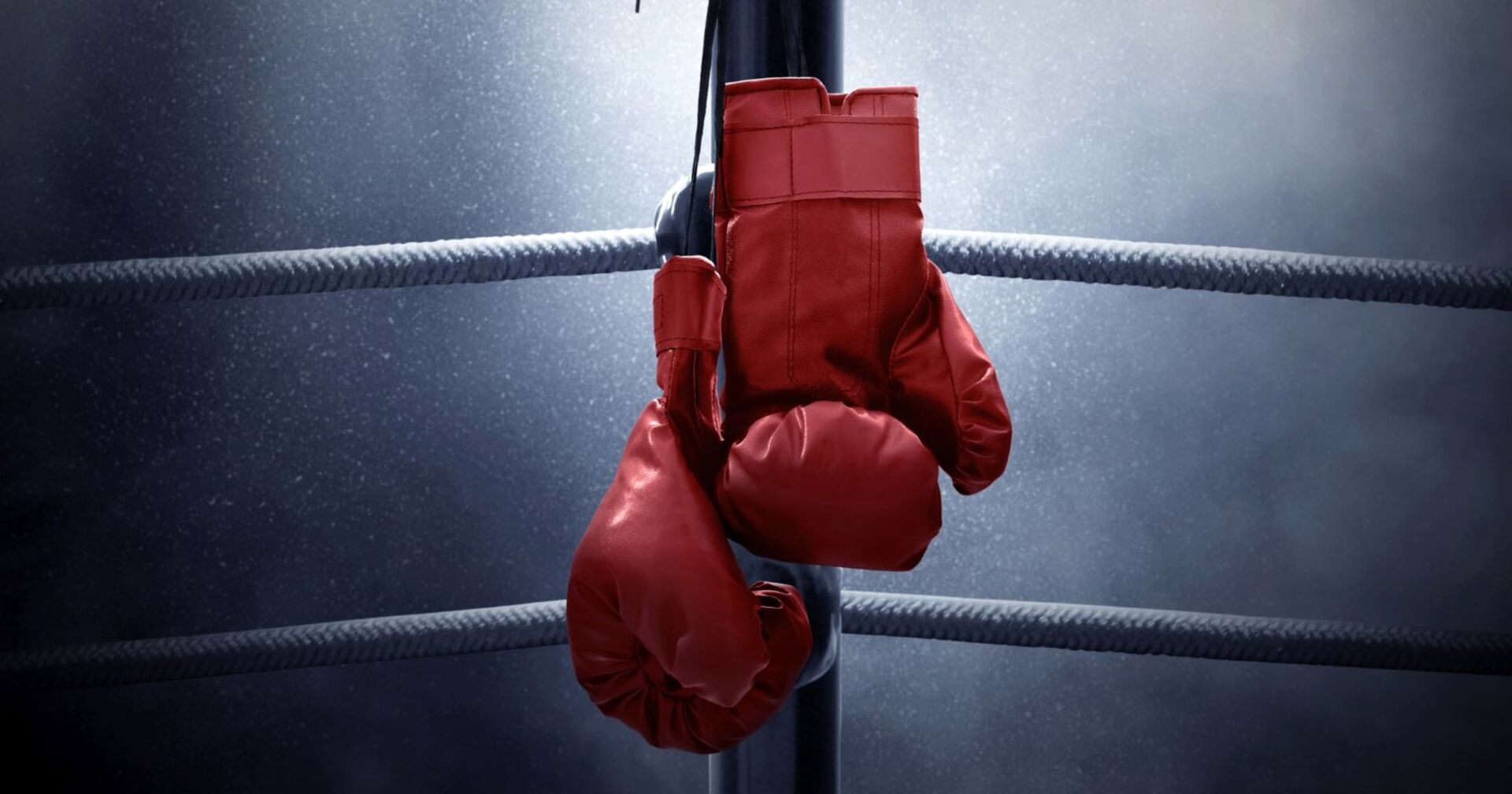 Rote Boxhandschuhe hängen in einem Boxring.