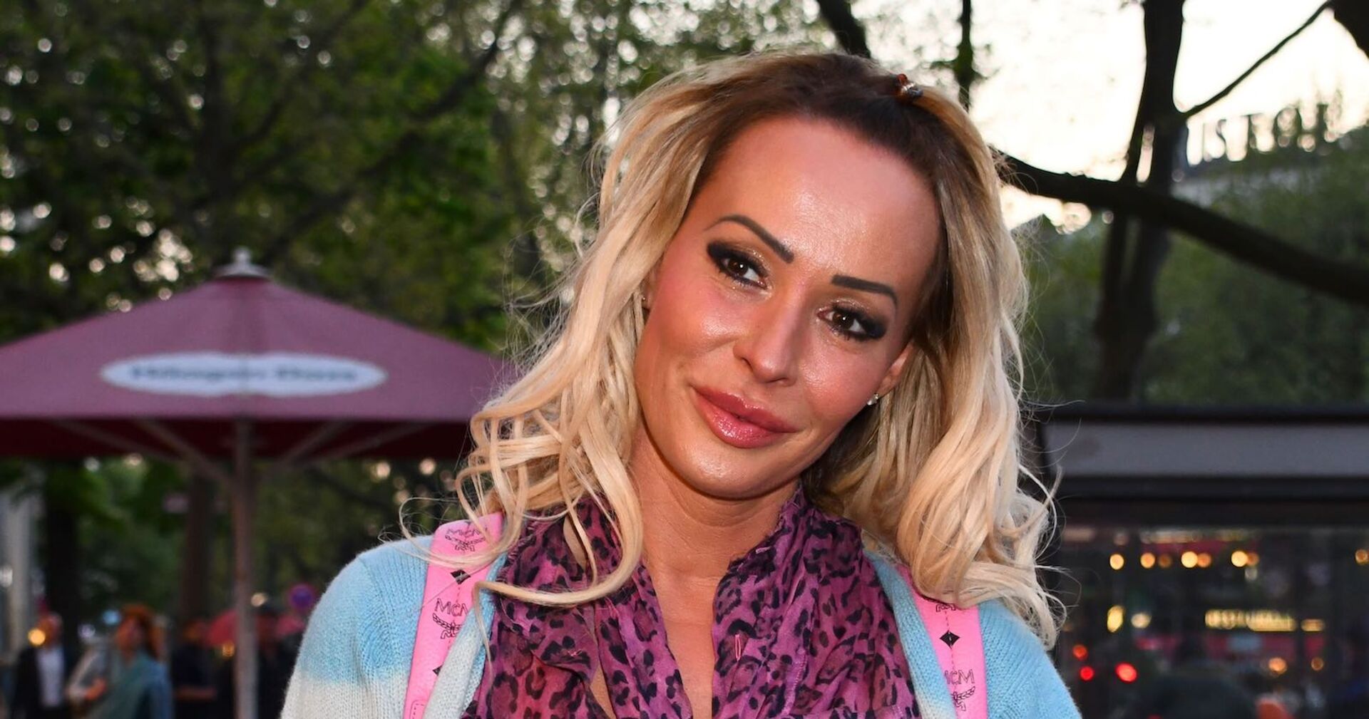 Cora Schumacher mit offenem, gewelltem, blondem Haar und Leopardenschaal.