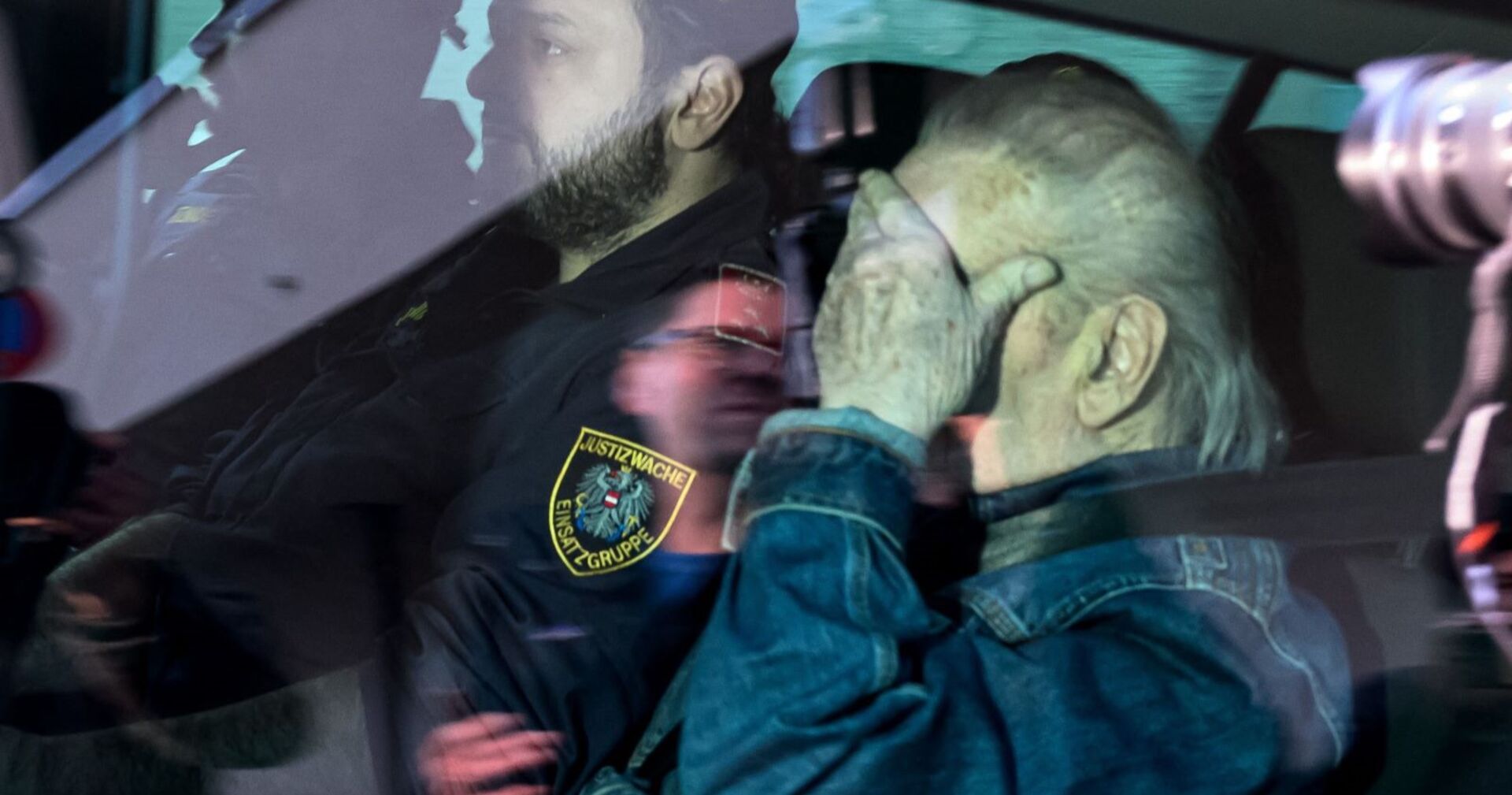 Josef Fritzl in einem Polizeiauto in Polizeibegleitung, er verdeckt sein Gesicht mit der Hand