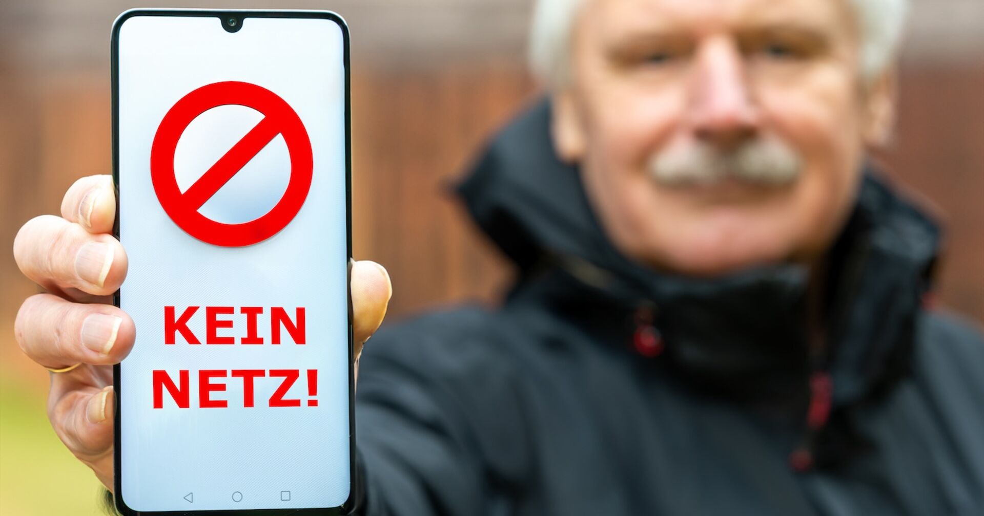 Eine Mann hält eine Handy mit einer &quot;Kein Netz&quot;-Aufschrift in die Kamera.