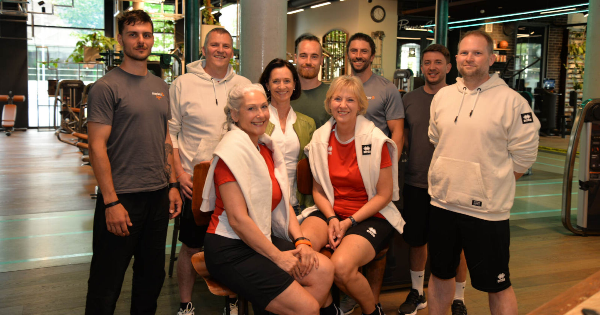 Mehrere Männer und Frauen posieren für ein Gruppenfoto in einem Fitnessstudio