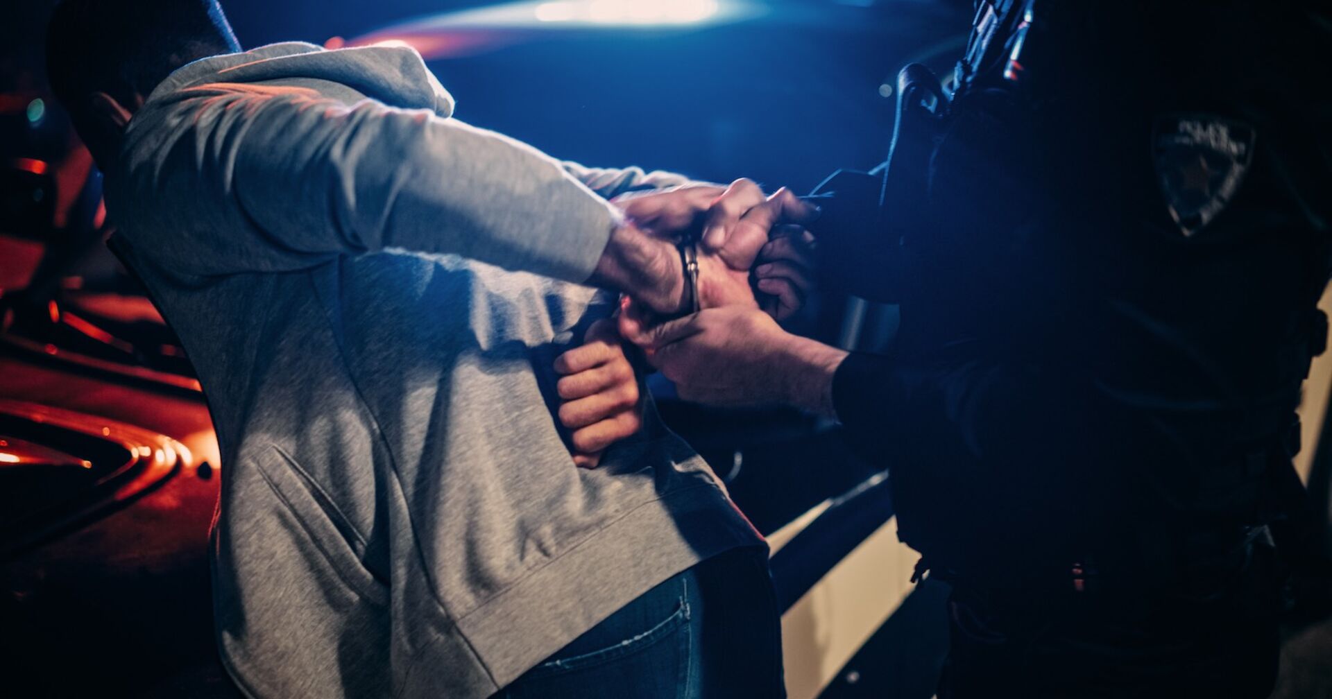 Ein Mann wird von einem Polizisten mit Handschellen festgenommen.