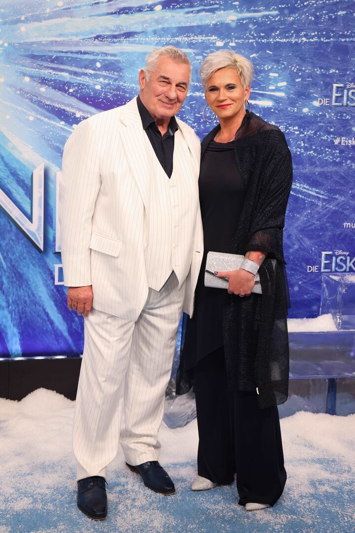 Heinz Hoenig und Annika Kärsten Hoenig bei einer Premiere. Er trägt weiß und sie schwarz.