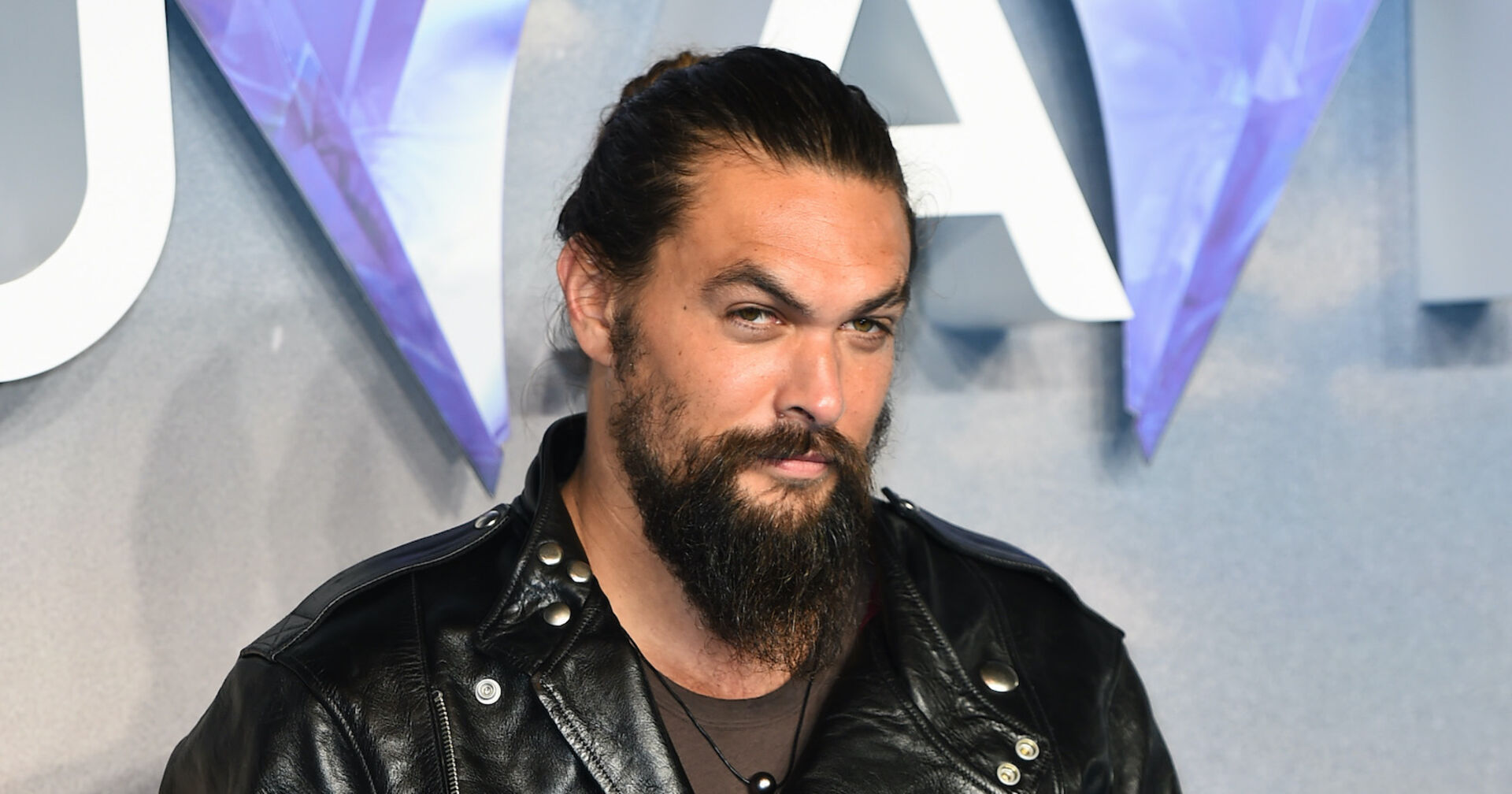 Jason Mamoa mit einem Bart und einer schwarzen Lederjacke.