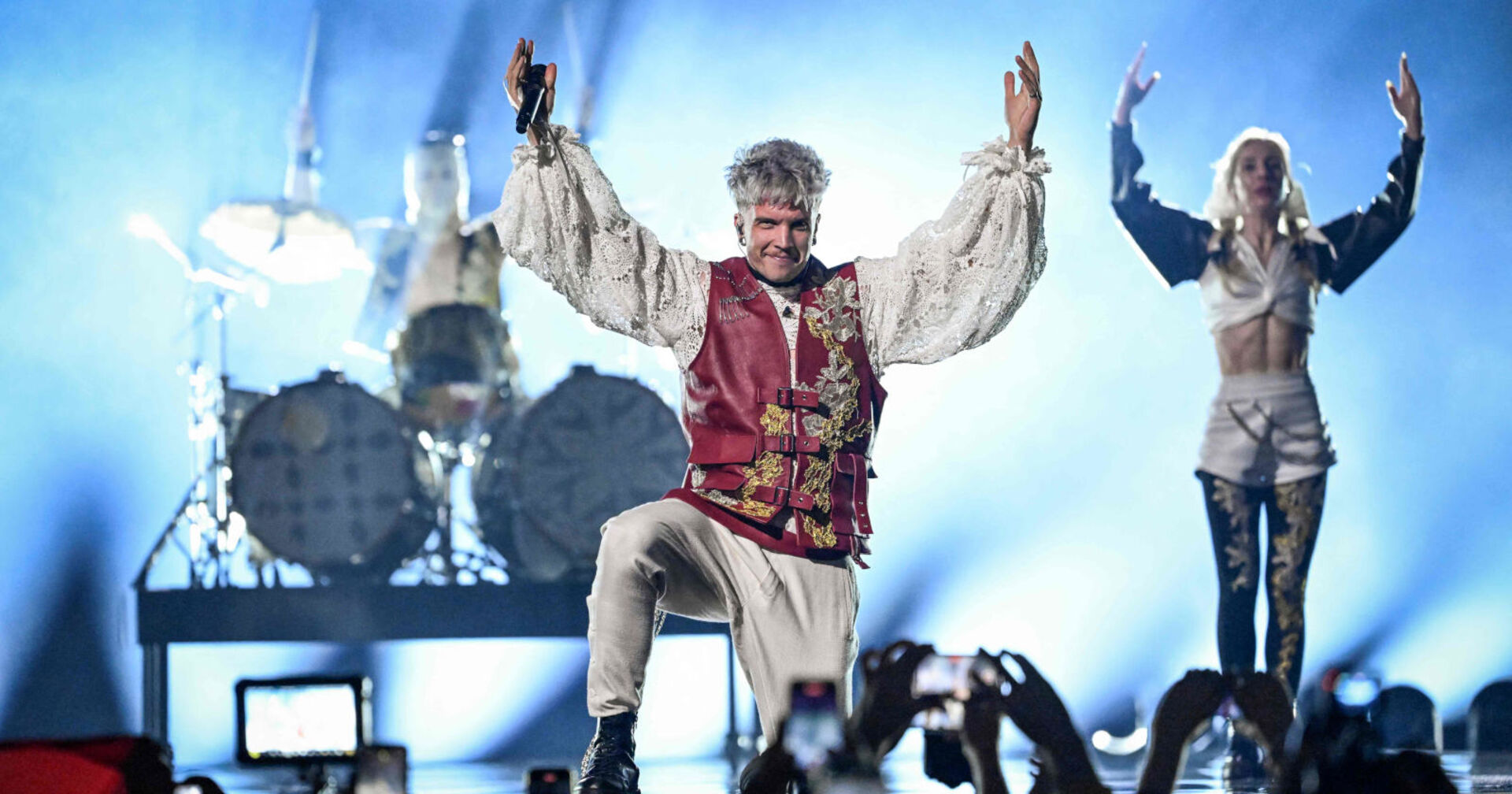 Ein Mann in mittelalterlichem Outfit steht auf der Bühne und hebt die Hände nach oben