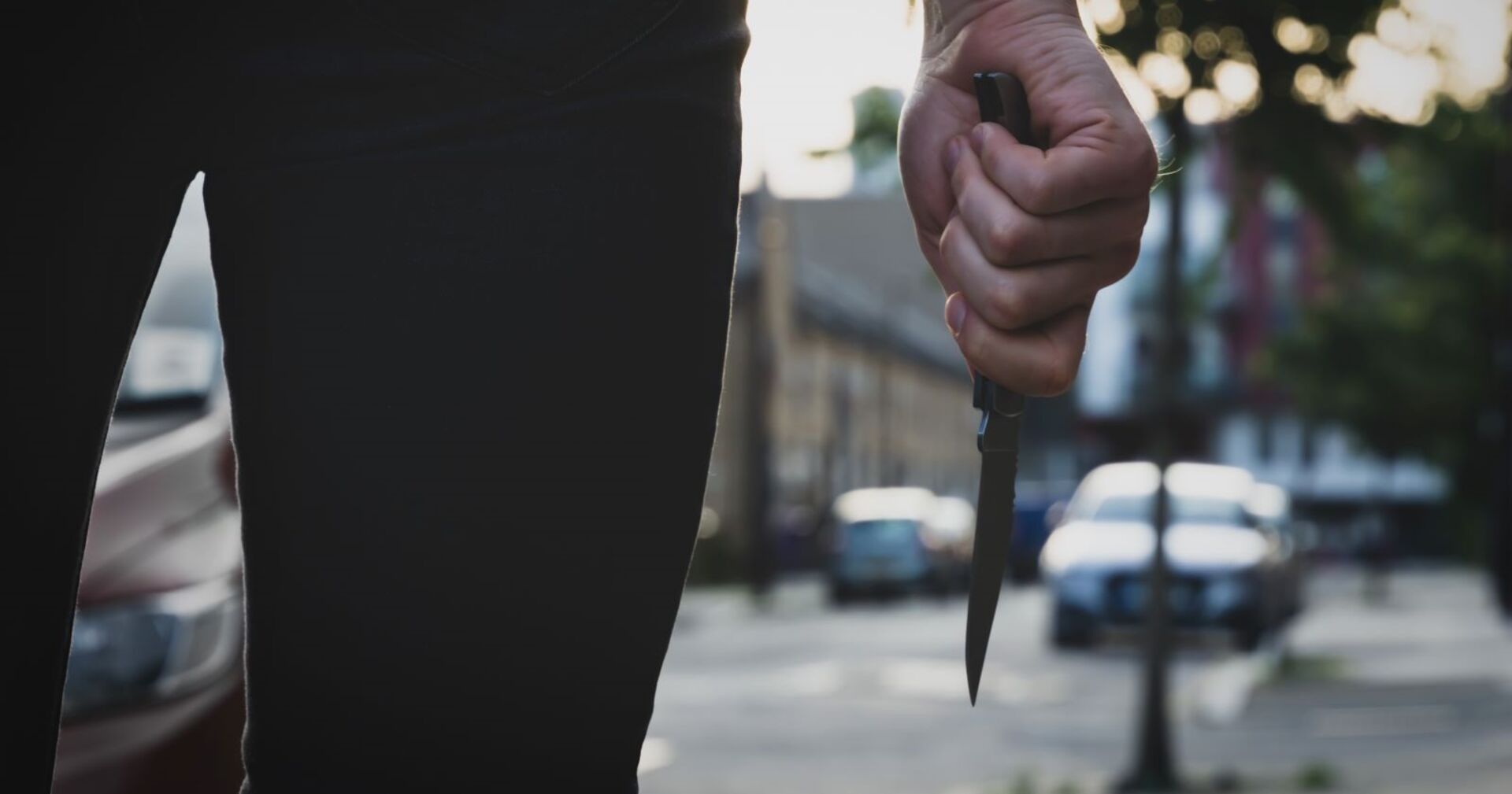 Ein Mann steht in einer Straße und hält ein Messer in der Hand.