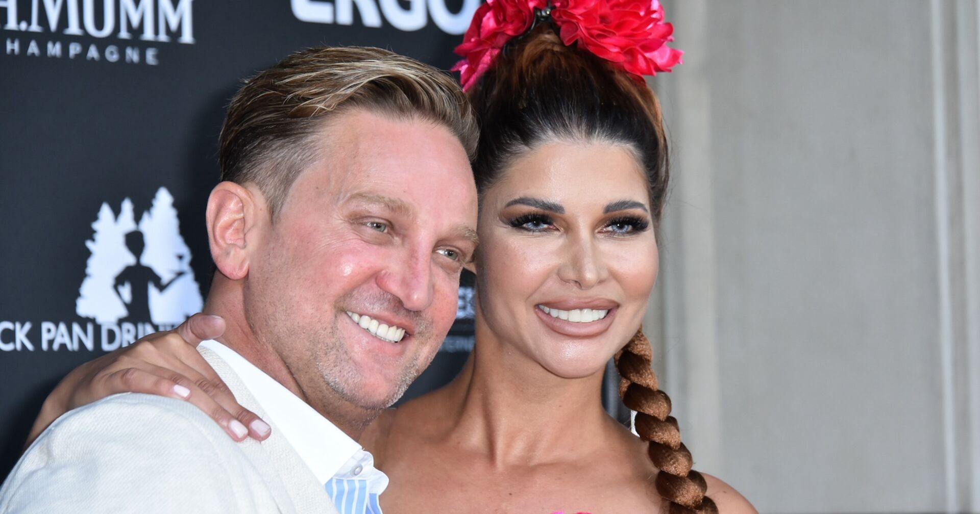 Micaela Schäfer mit ihrem Mann Adriano bei einem Event. Sie hat rote Rosen am Kopf.