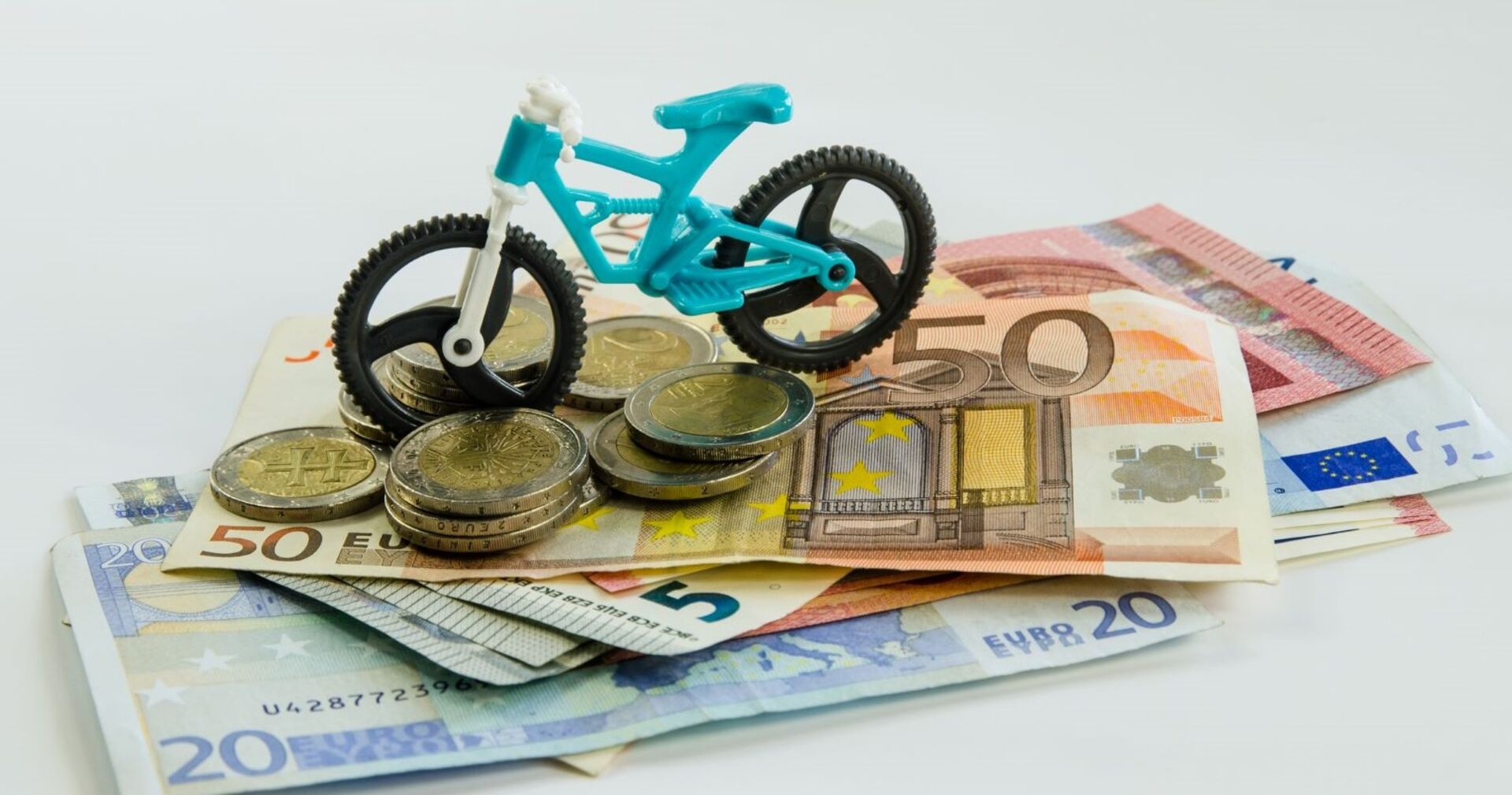 Ein Spielzeugfahrrad steht auf einem Stapel Geldscheine