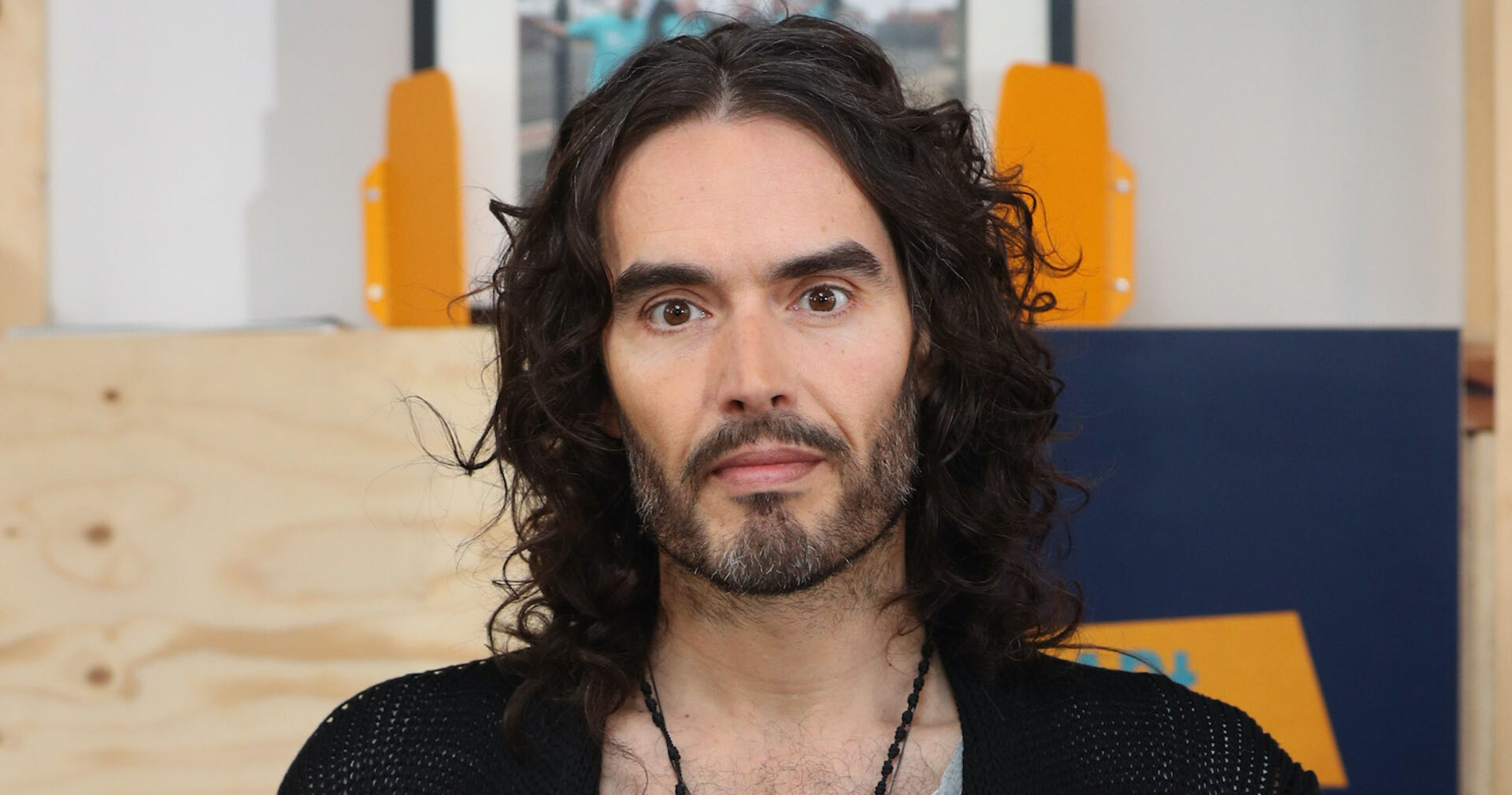Russell Brand mit offenen, gelockten Haaren.