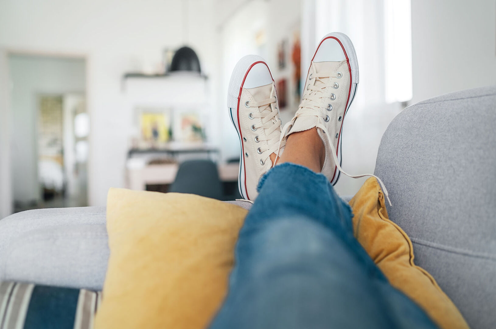 Frau mit Sneakers liegt auf der Couch | Credit: iStock.com/Solovyova