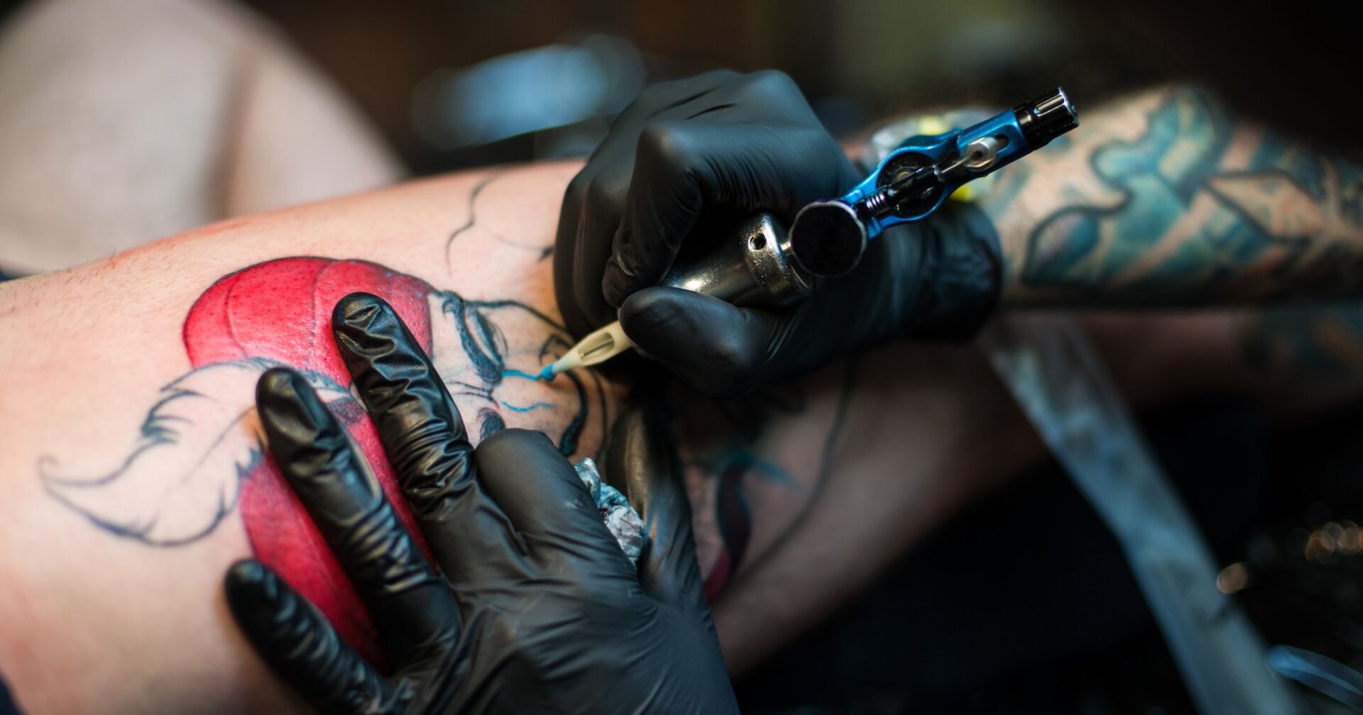 Ein Tätowierer sticht ein Tattoo.