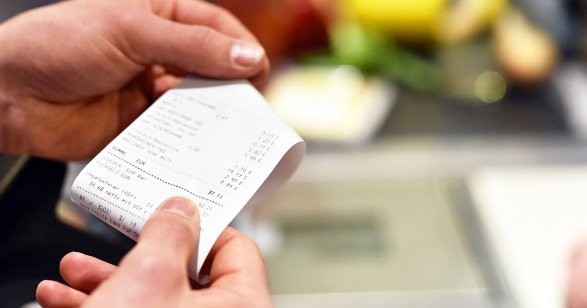 Jemand hält eine Supermarkt-Rechnung in der Hand.