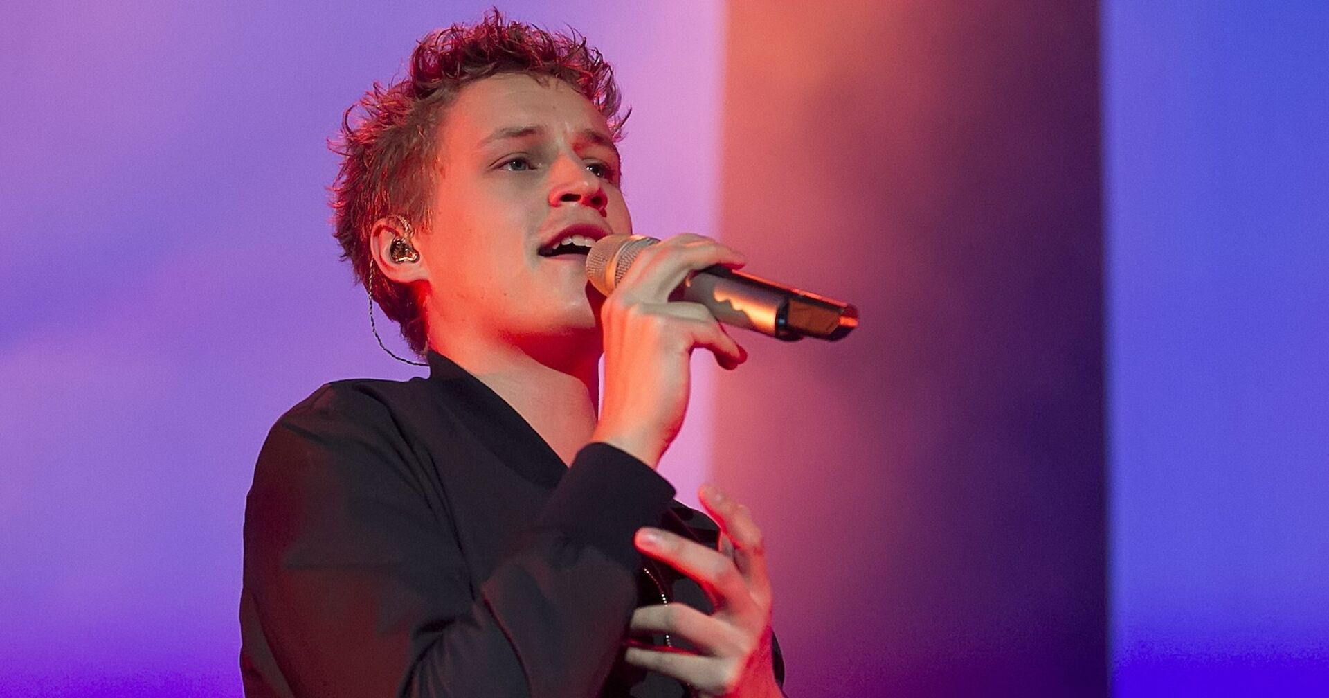 Tim Benzko auf der Bühne mit einem Mikrofon.