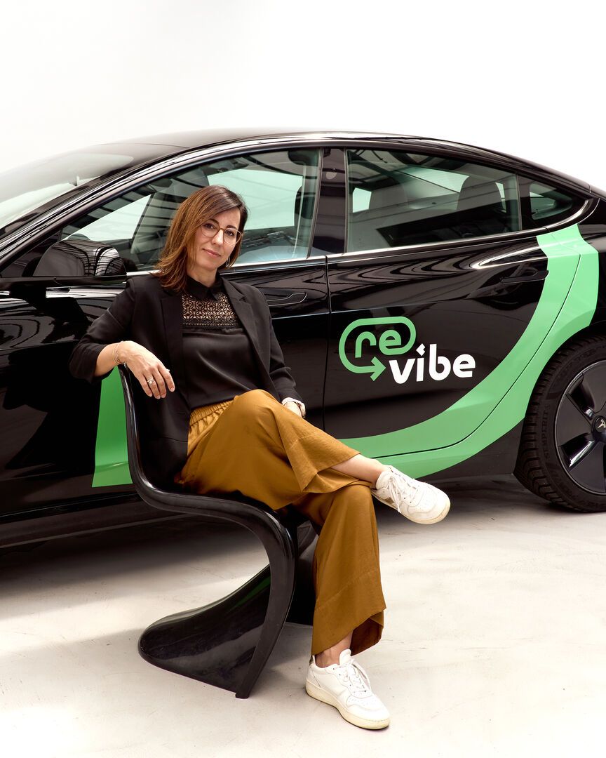 Porträt auf einem Sessel sitzend vor gebrandetem Auto