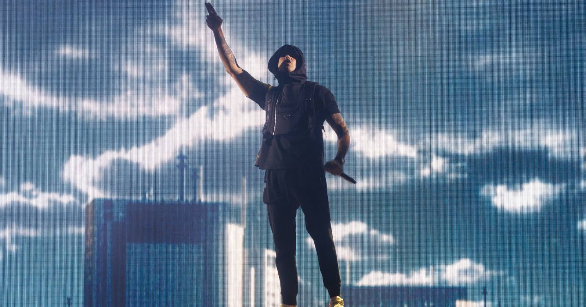 RAF Camora auf der Bühne vor einer riesigen Leinwand, auf der dunkle Wolken zu sehen sind