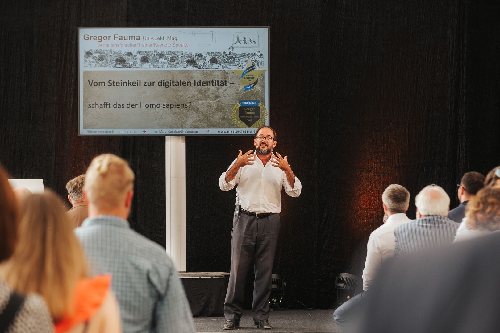 Redner auf der Bühne stehend und gestikulierend