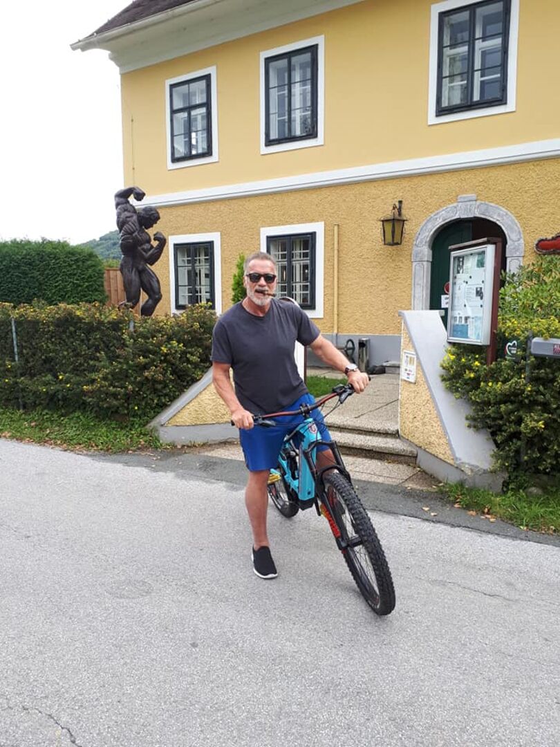 Ein Mann auf einem Fahrrad vor einem gelben Haus