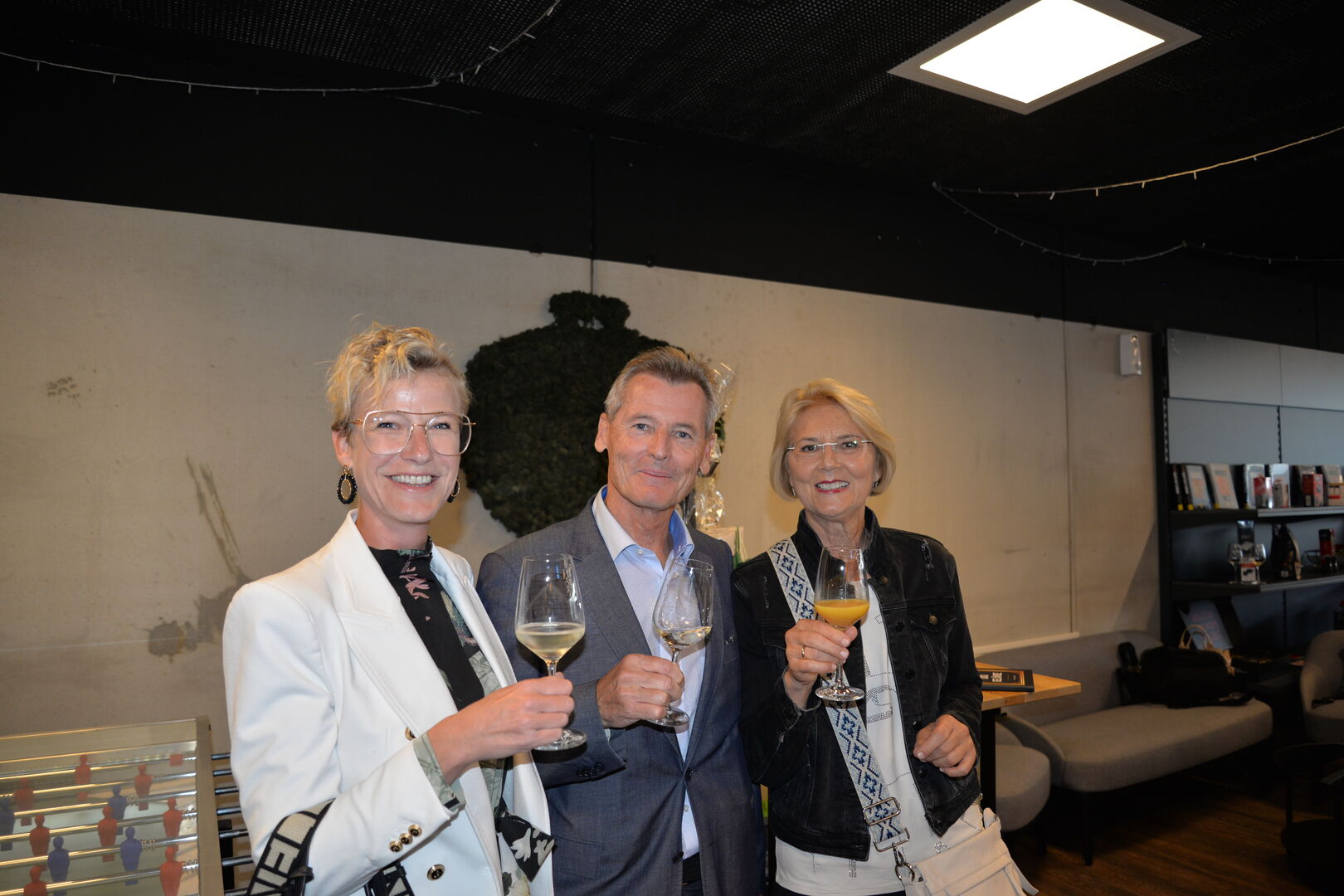 Zwei Frauen und ein Mann mit Sektgläsern in der Hand