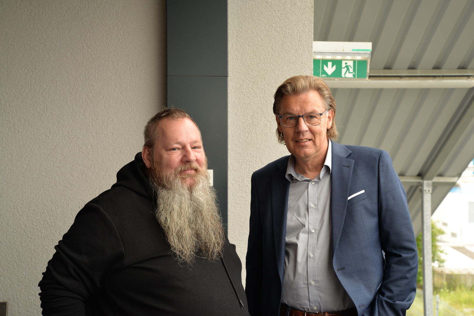 Zwei Männer stehen nebeneinander auf einem Balkon