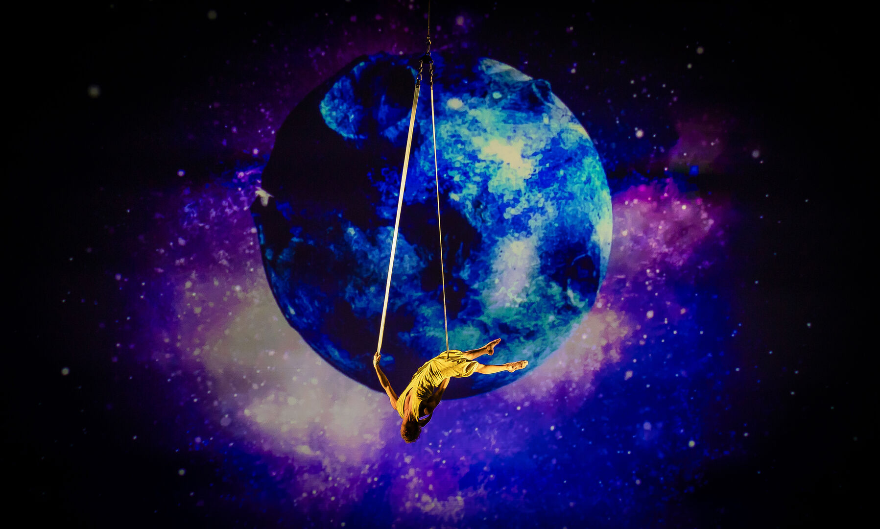 Ein Akrobat hängt in den Seilen