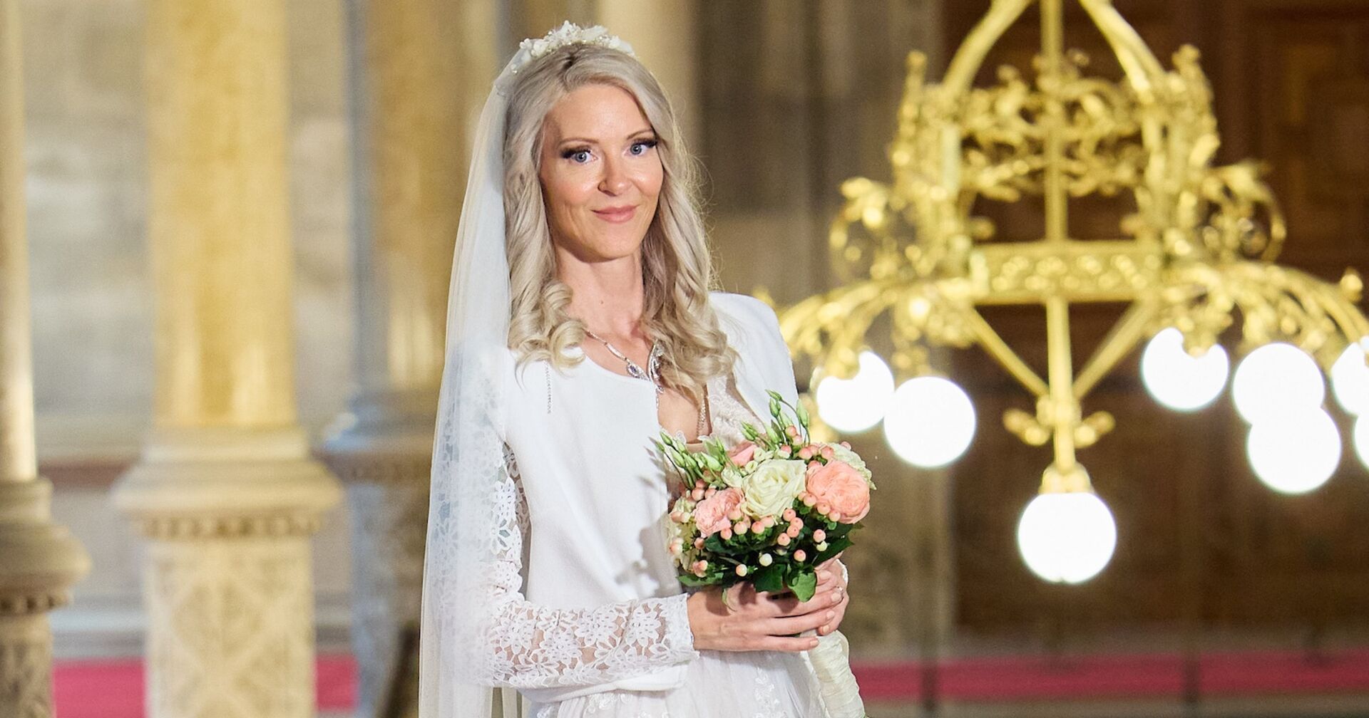 Simone Lugner mit in einem weißen Brautkleid, einem Blumenstrauss und einem weißen Schleier.