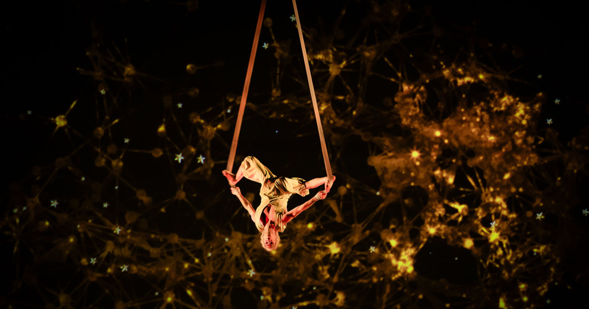 Ein Akrobat hängt kopfüber zwischen zwei Seilen