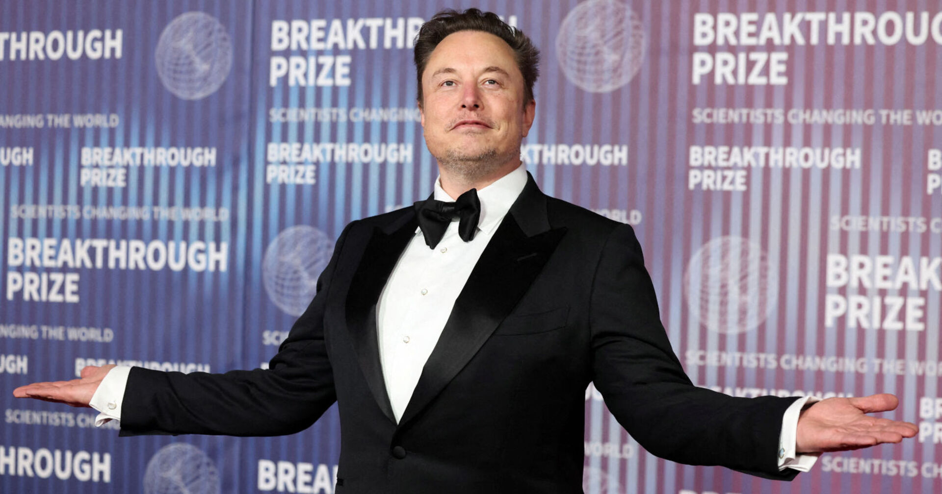 Ein Mann in einem Smoking steht mit ausgebreiteten Händen