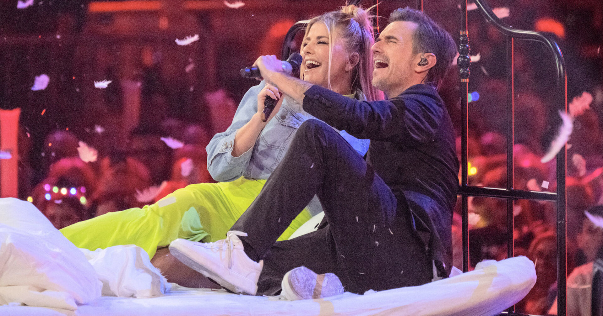 Beatrice Egli und Florian Silbereisen in einem Bett auf einer Bühne.