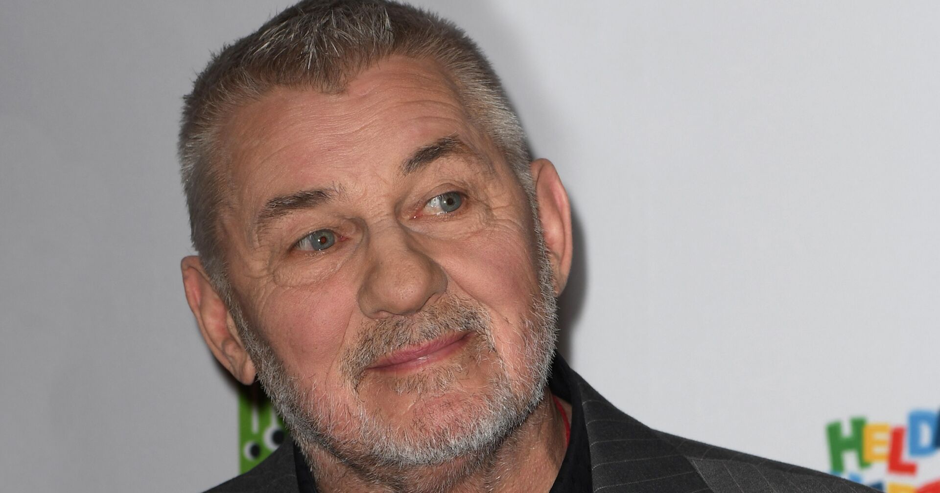 Heinz Hoenig vor einer Fotoleinwand.