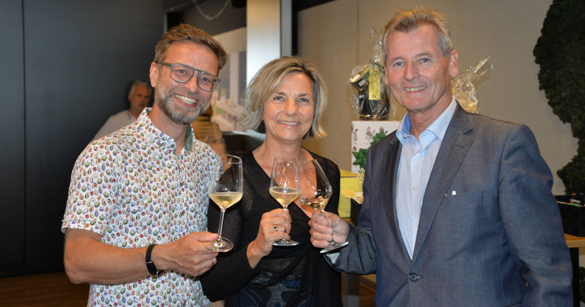 Zwei Männer und eine Frau stoßen mit einem Glas Sekt an
