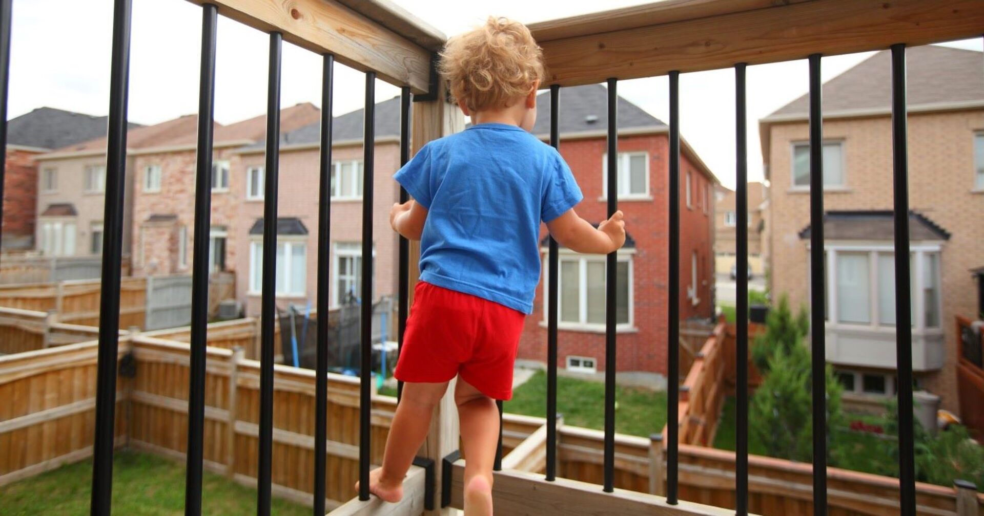 Ein kleiner Bub steht allein auf einem Balkon.