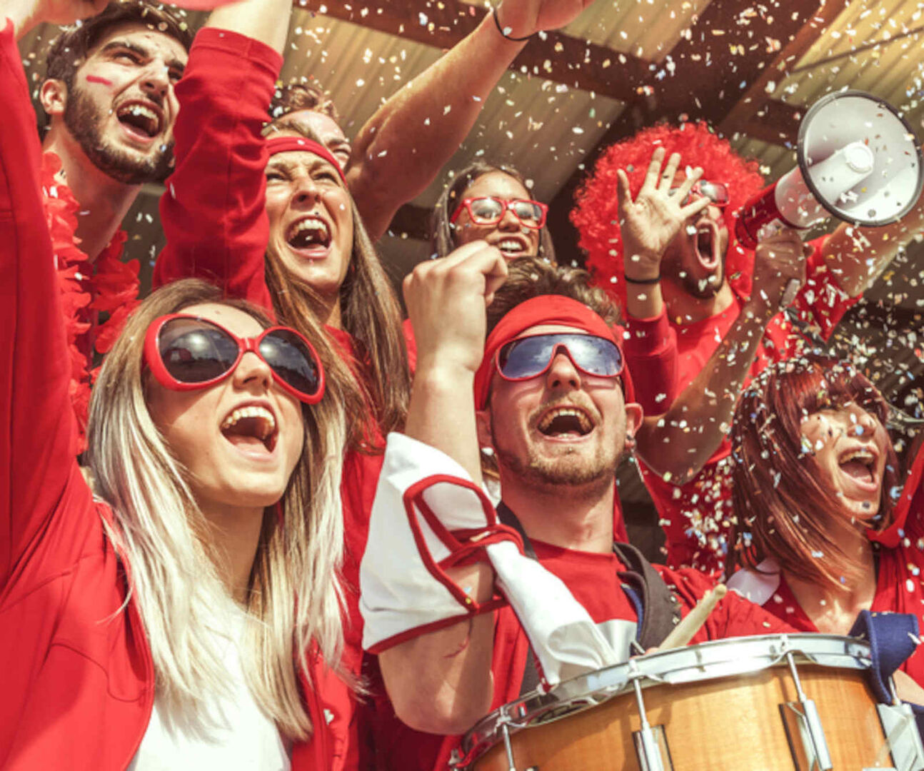 Mehrere Fußballfans sind in Rot gekleidet und jubeln