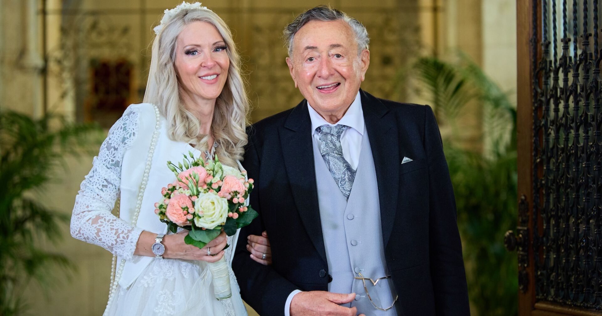 Richard Lugner und Simone Reiländer beim Standesamt in einem weißen Kleid. Lugner trägt einen Smoking.