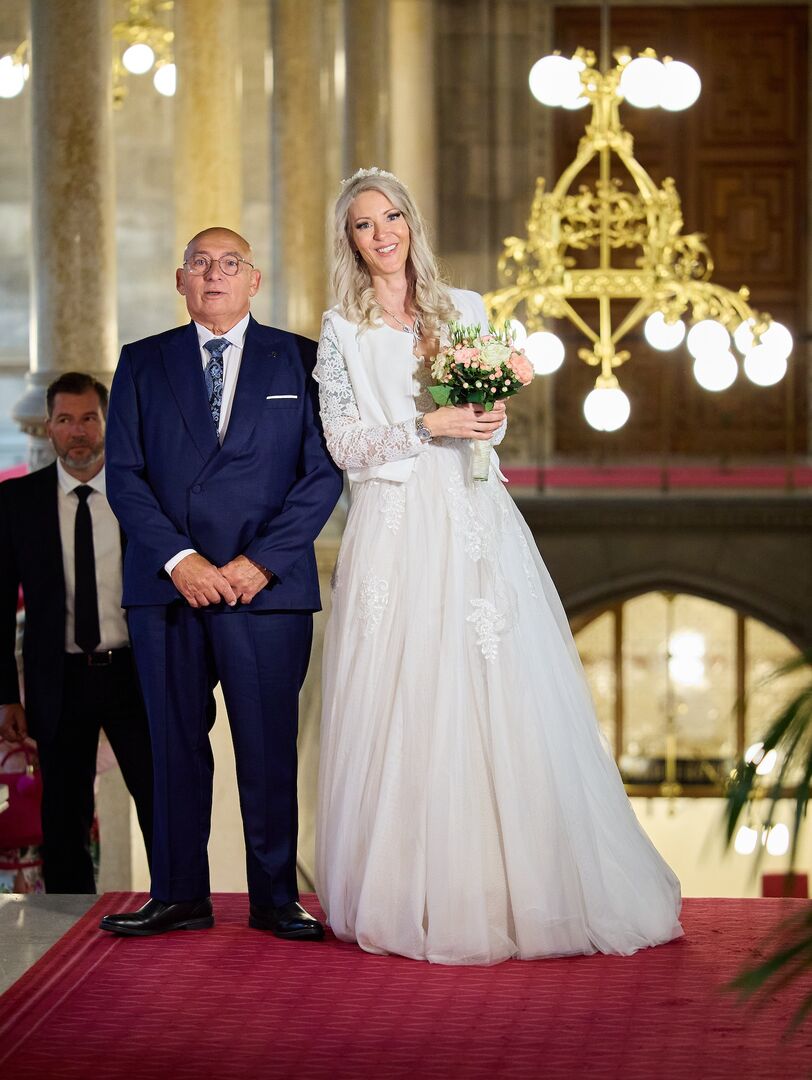 Simone und ihr Vater vor der Trauung. Sie trägt ein langes weißes Hochzeitskleid und ihr Vater einen blauen Anzug.
