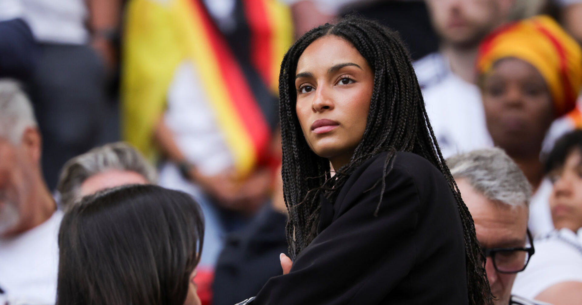 Eine Frau mit dunklen Haaren steht auf einer Tribüne im Stadion