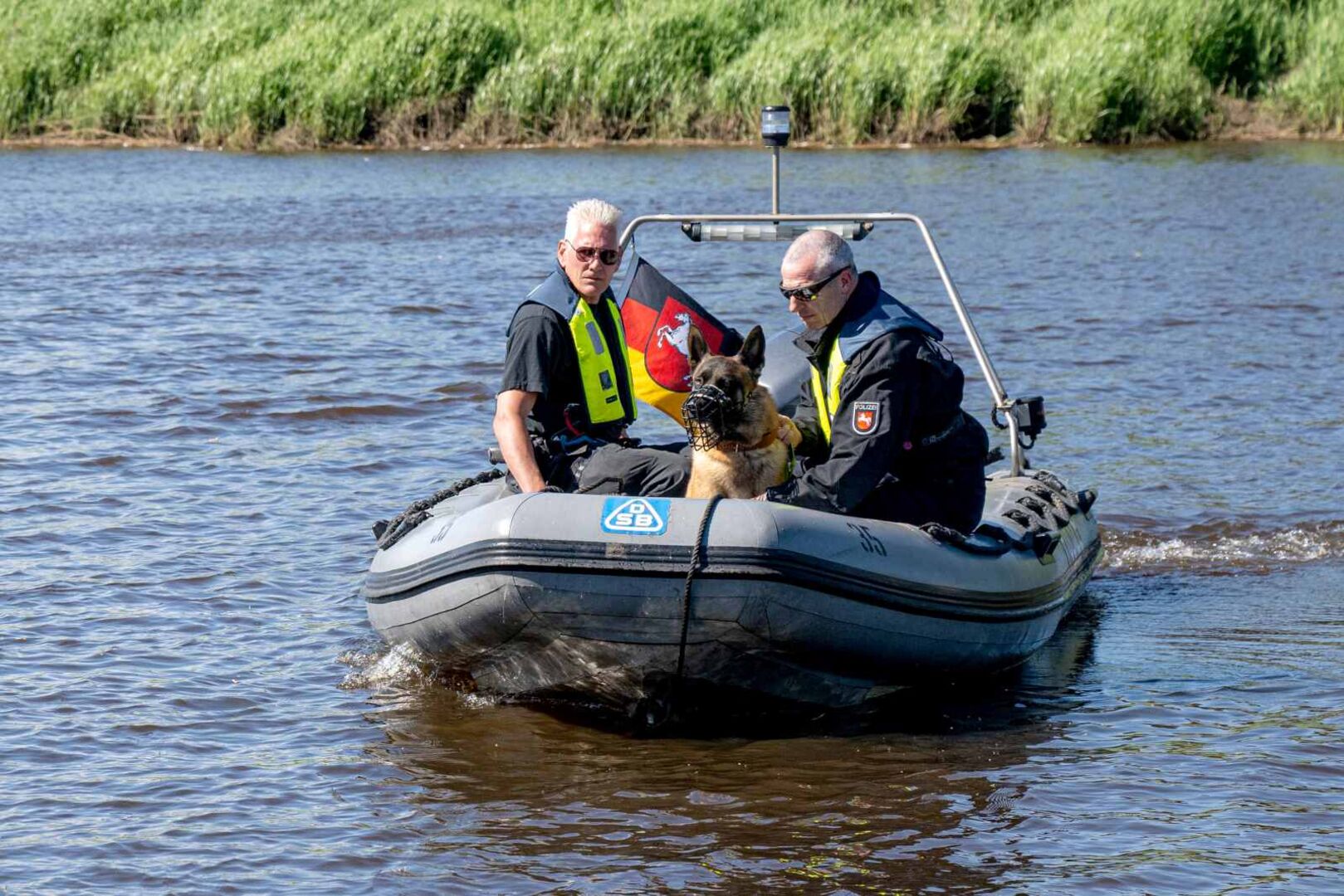 Ermittler und ein Spürhund mit einem Boot auf dem Fluss.