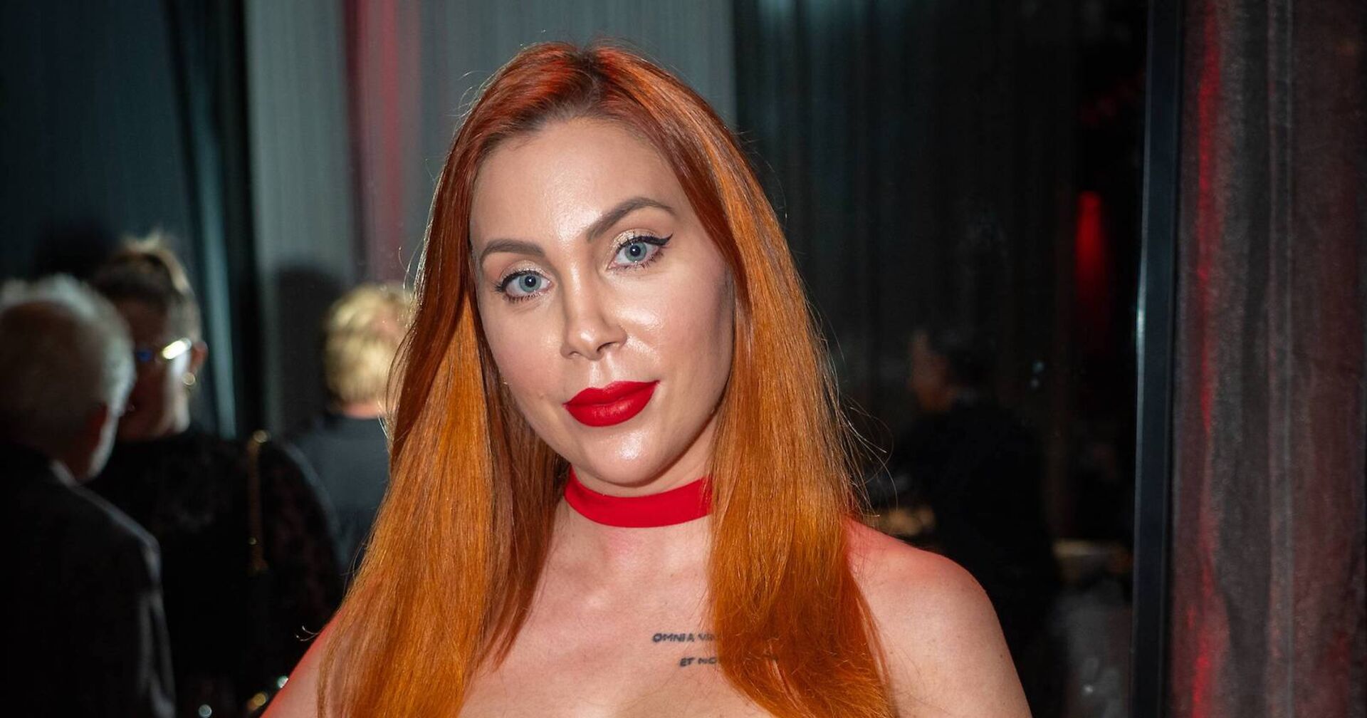 Tara Tabitha mit kupfernen langen glatten Haaren und einem knallroten Lippenstift.