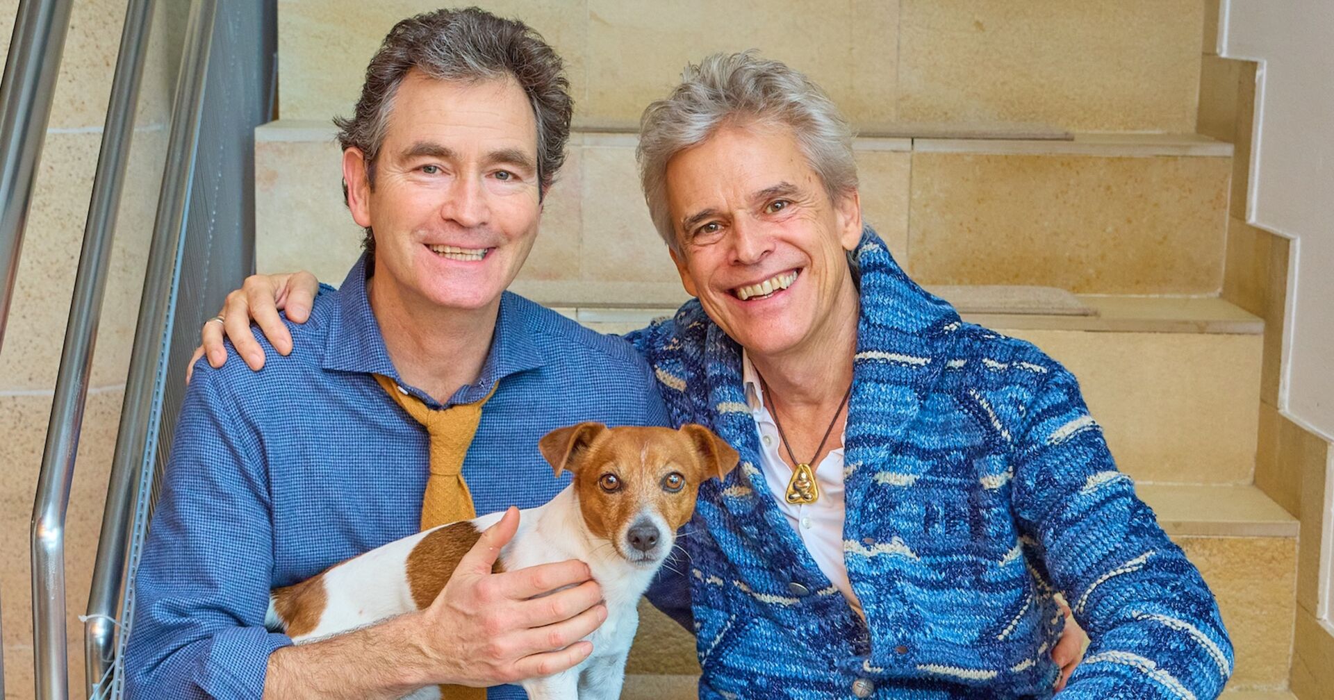 Thomas Brezina und sein Ehemann Ivo Belajic und Hund Joppy in einem blauen Hemd.