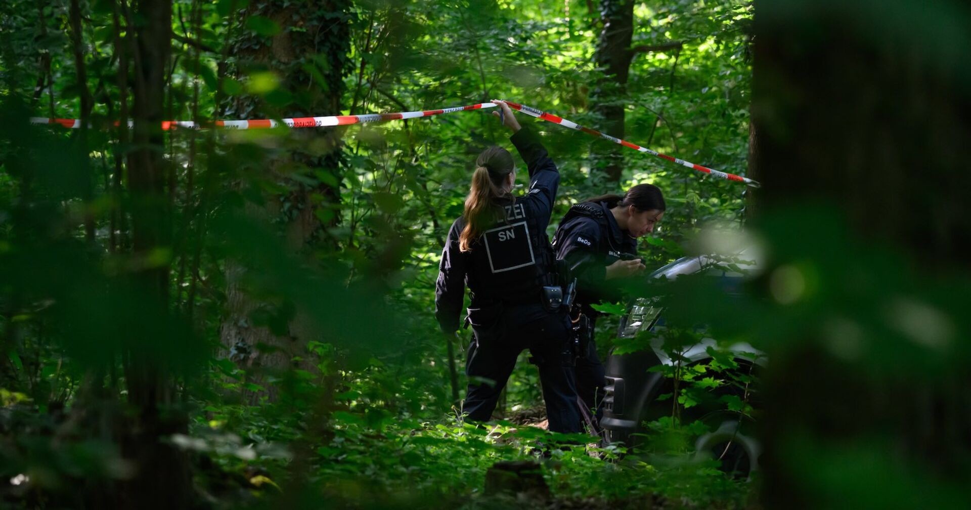 Zwei Polizisten am Tatort im Wald.