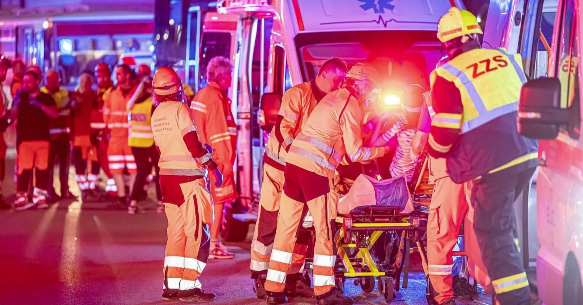 Blaulicht und Einsatzfahrzeuge bei Nacht, Rettungskräfte kümmern sich um Verletzte.