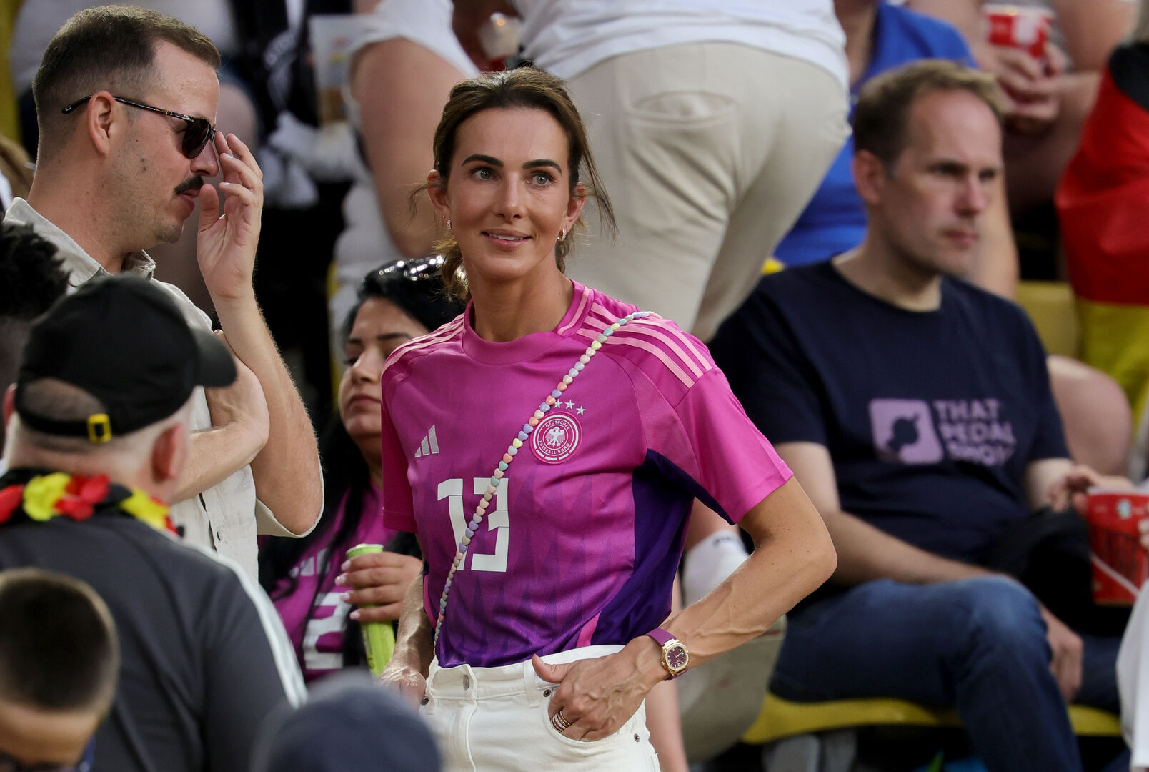 Eine Frau im pinken Fußballtrikot steht auf der Tribüne