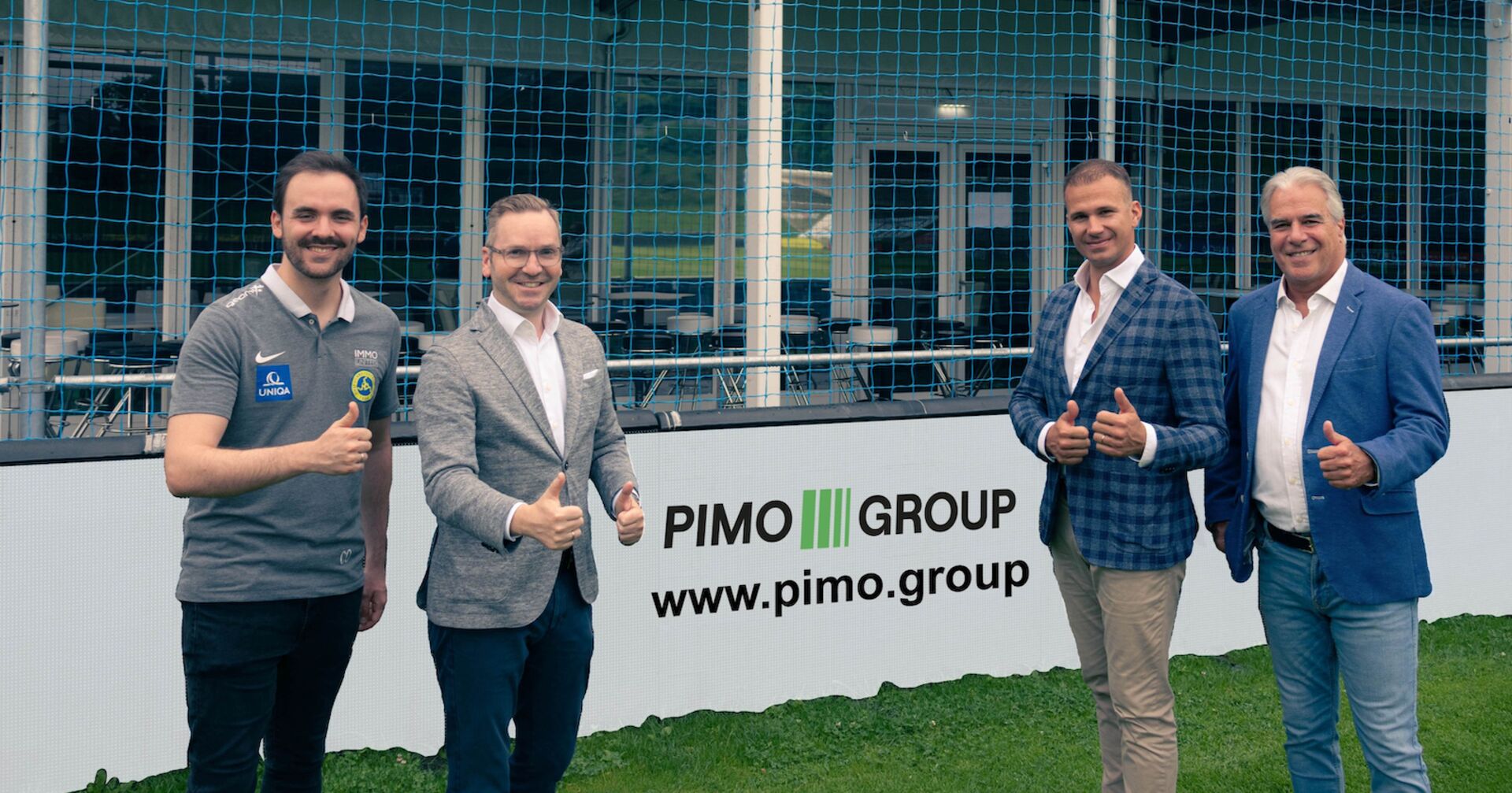 Vier Männer stehen vor Bandenwerbung