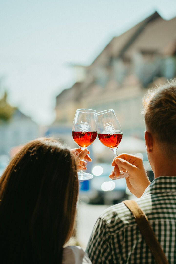 Ein Paar stoßt vor einer Stadtkulisse mit Wein an