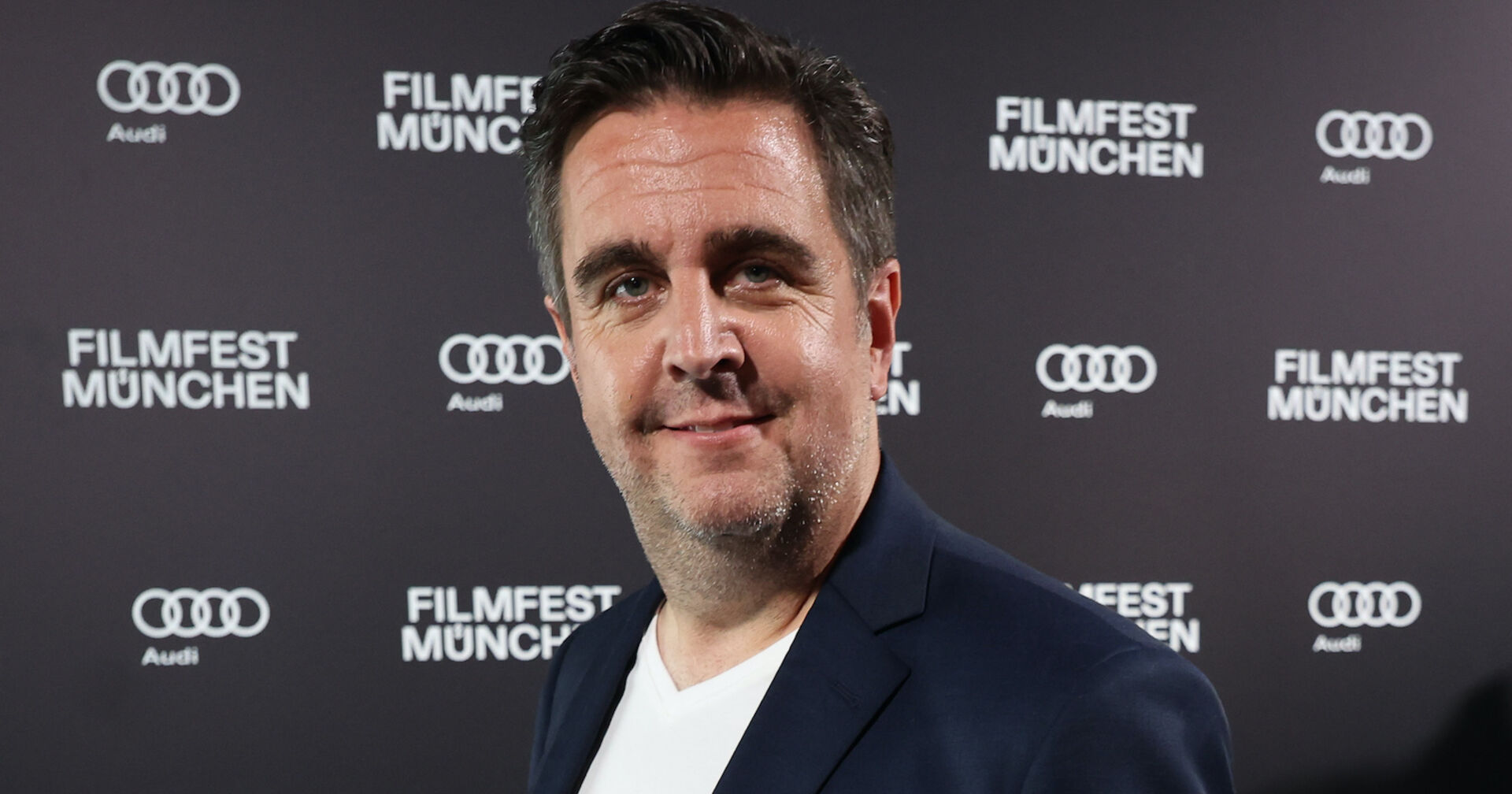 Bastian Pastewka bei vor einer Fotoleinwand.