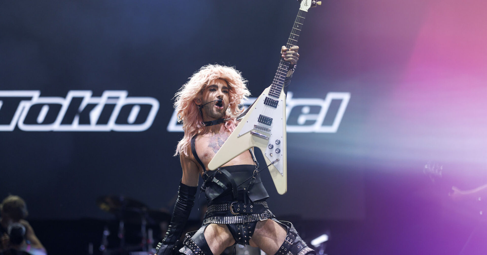 Bill von Tokio Hotel mit einem engen Lederoutfit und einer Gitarre auf der Bühne.