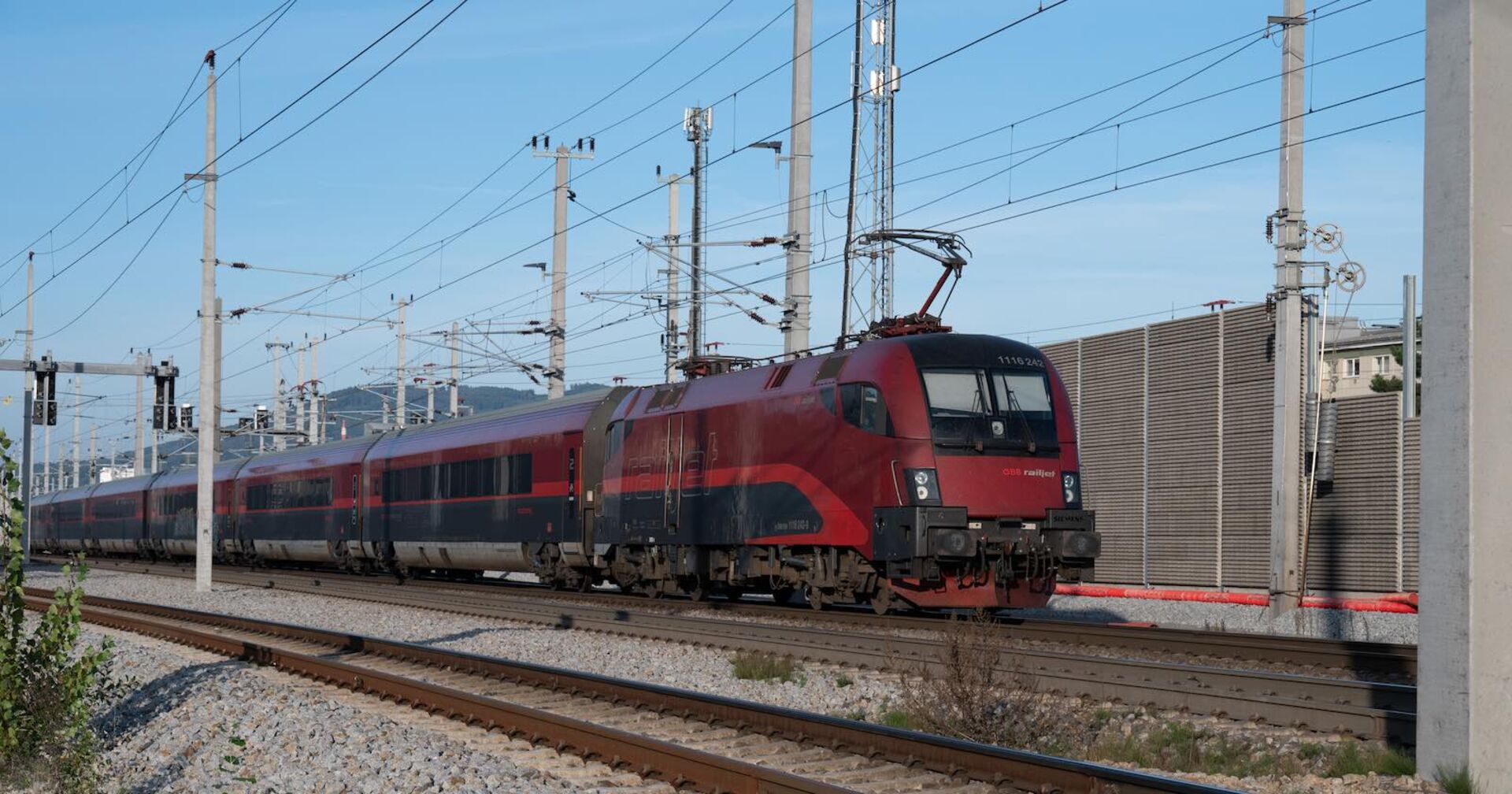 Ein ÖBB-Zug in einem Bahnhof, darüber die Stromleitungen.