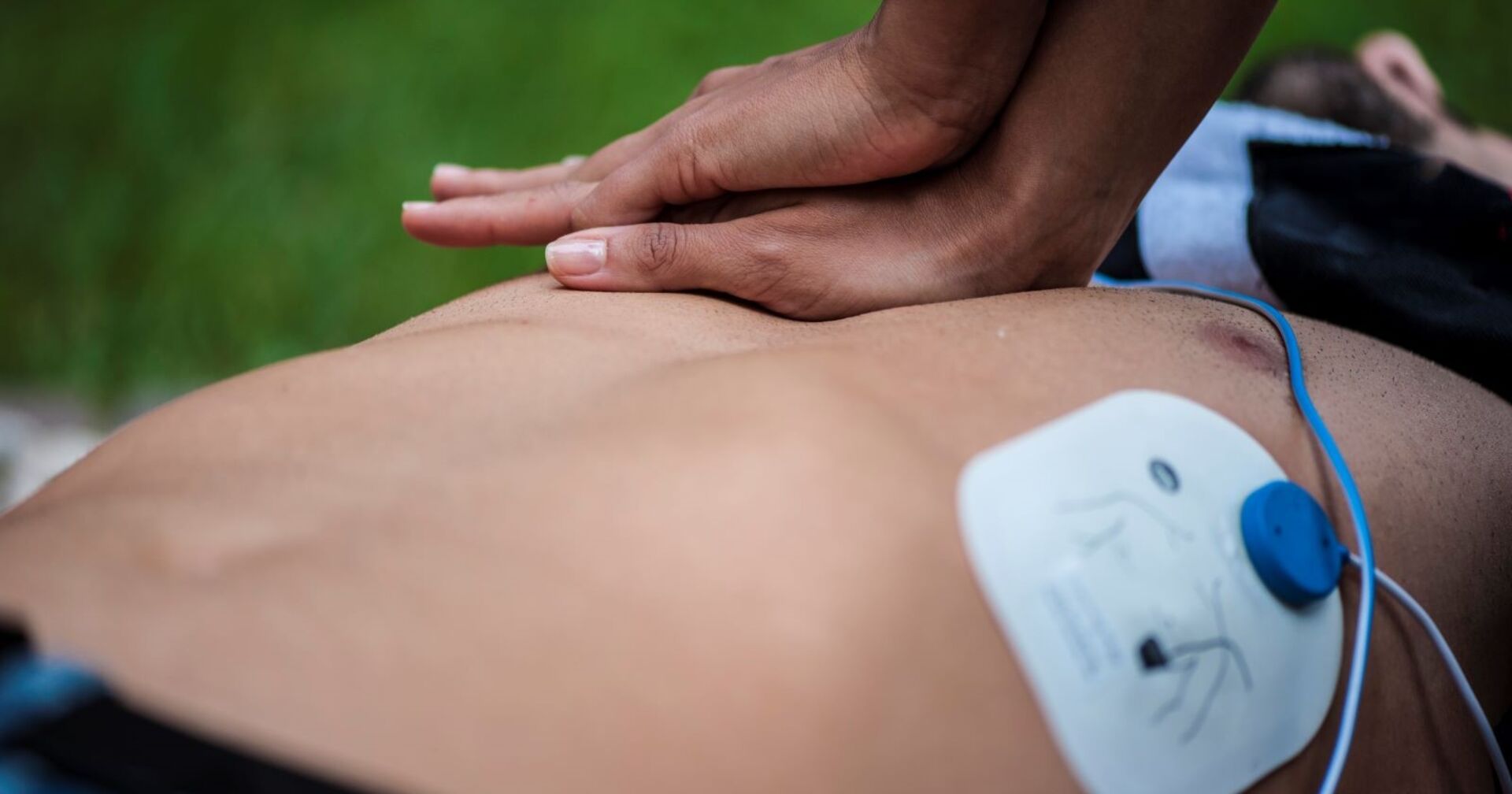 Rettungskraft führt Herzdruckmassage durch. Ein Defibrillator ist im Einsatz.