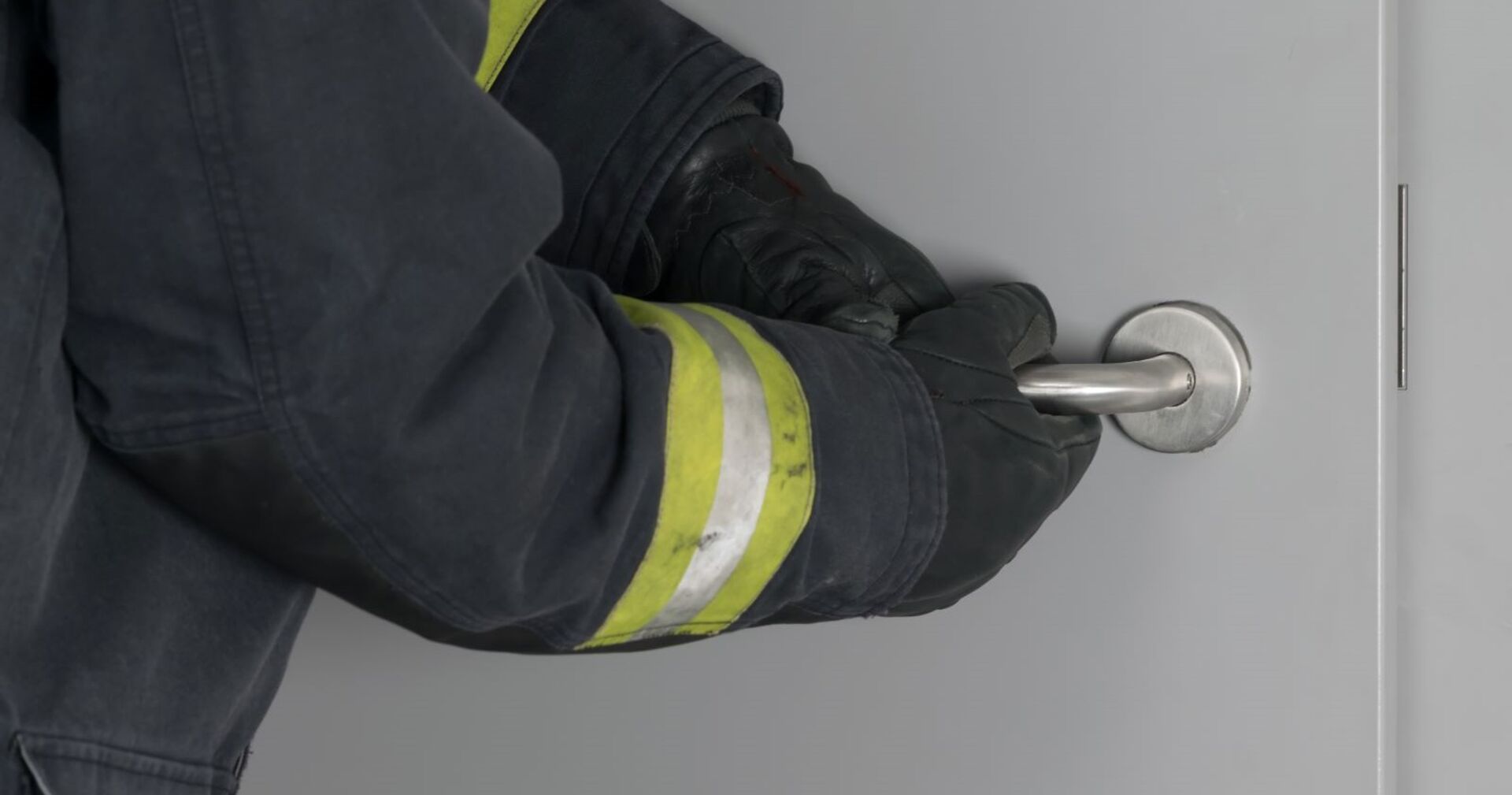 Feuerwehrmann bricht eine Wohnungstüre auf.